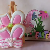 Adorable bunny ears iced cookie with pink frosting, green bow and decorative basket pattern
