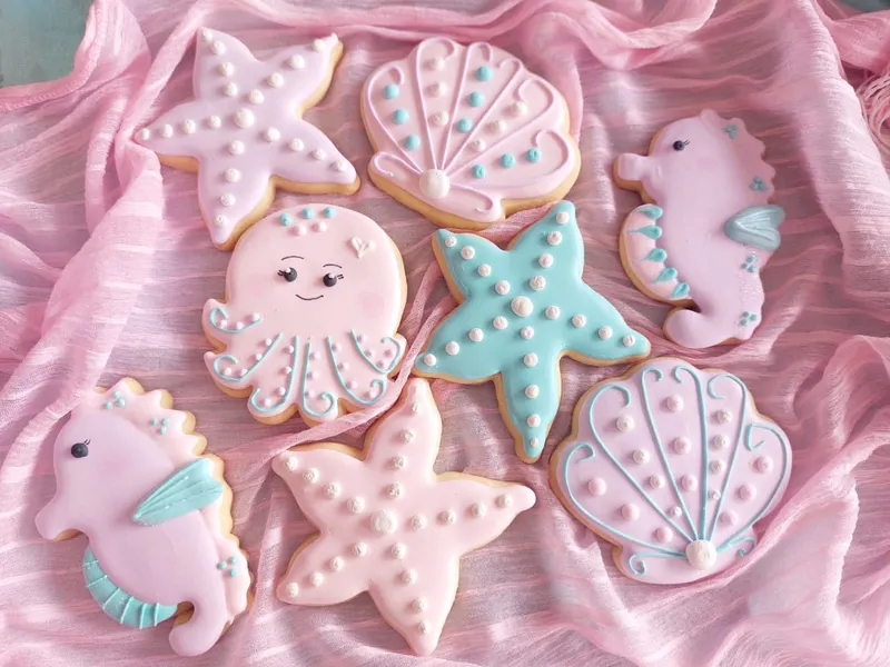 Beautiful handcrafted iced cookies and biscuits on pink fabric